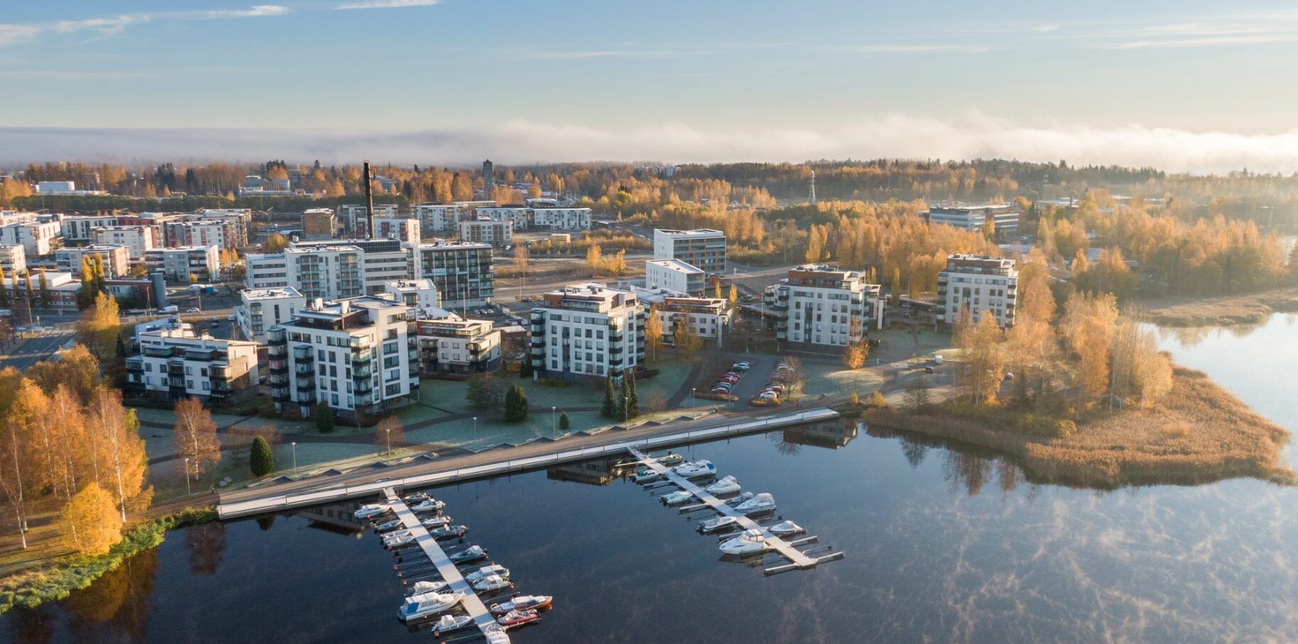 Droonilla otettu kuva järven rannalla olevasta kerrostaloalueesta.