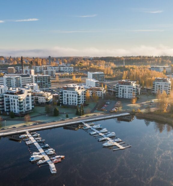 Droonilla otettu kuva järven rannalla olevasta kerrostaloalueesta.