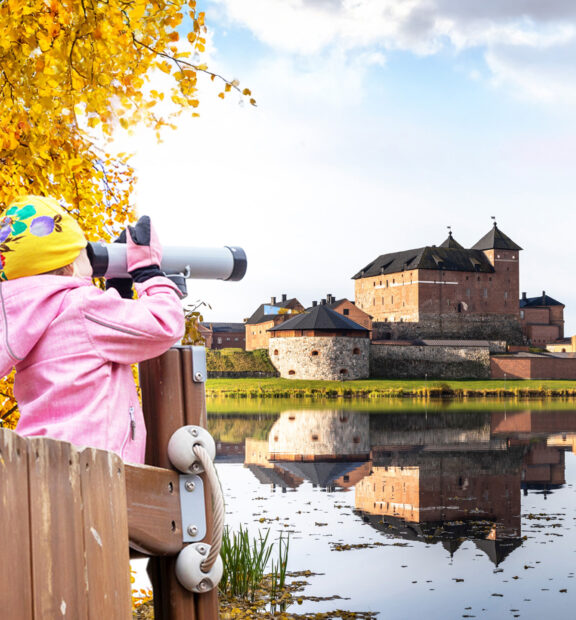 lapsi katsoo Hämeen linnaa kaukoputkella